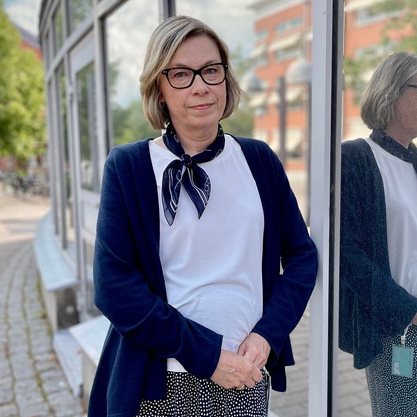 Karin Axelsson står utomhus och talar om AI vid en glasvägg