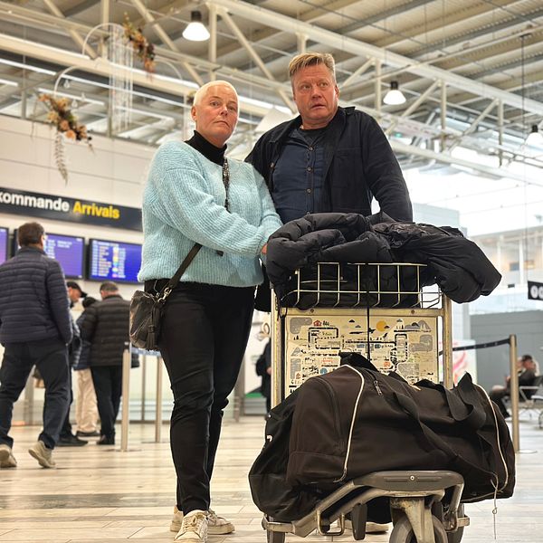 Pernilla Califf står bredvid Ulf Jonasson som håller i en rullvagn med deras bagage. I bakgrunden syns Landvetters ankomstterminal.