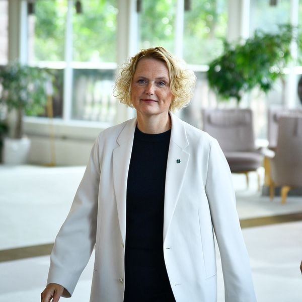 Två personer i formella kläder går tillsammans inomhus.