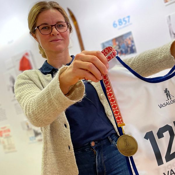 Vasaloppets pressansvarige Camilla Sany Swarén håller upp en nummerlapp och en medalj.