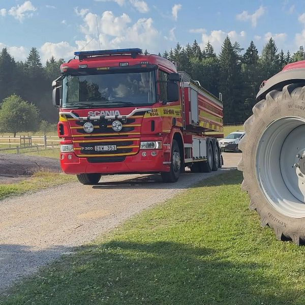 Brandbil och traktor vid avspärrat område nära Säbysjön efter skogsbrand.