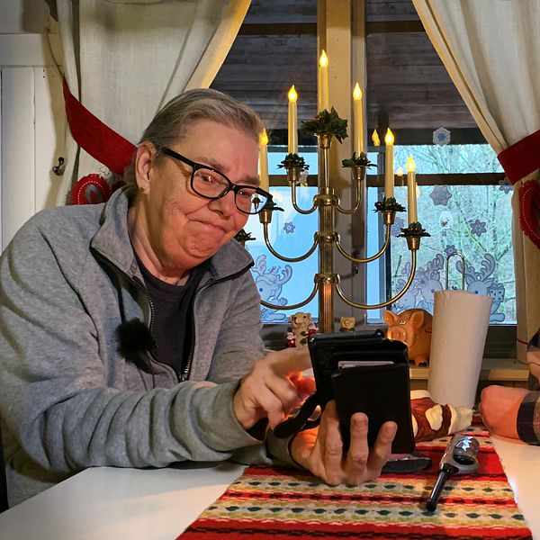 Två kvinnor (Carina Tvedahl-Lernsten och hennes fru Anette Lernsten) sitter vid köksbordet och tittar på elräkningen på en mobiltelefon.