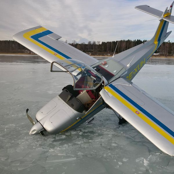 Flygplan på is med ena vingen och propellern delvis under isen.