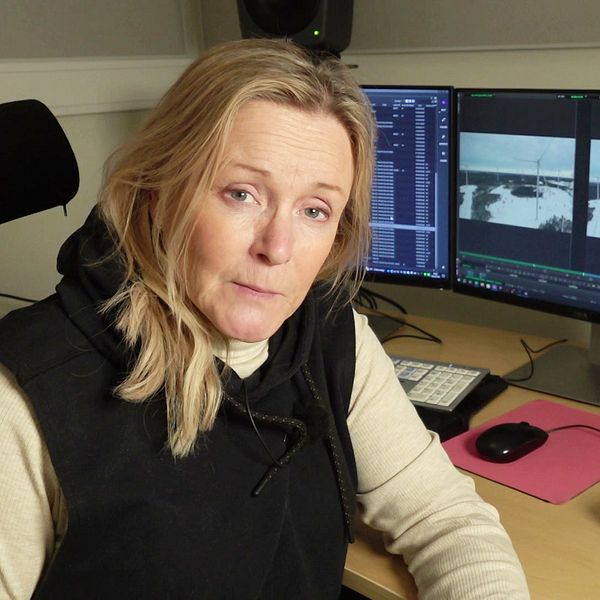 SVT:s reporter Randi Gitz sitter framför dataskärmar med bilder från vindkraftspark