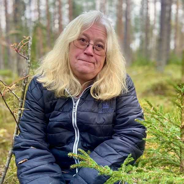 Carina Olhson (C), centerpolitiker i Nordanstig, sitter på huk i en skog.