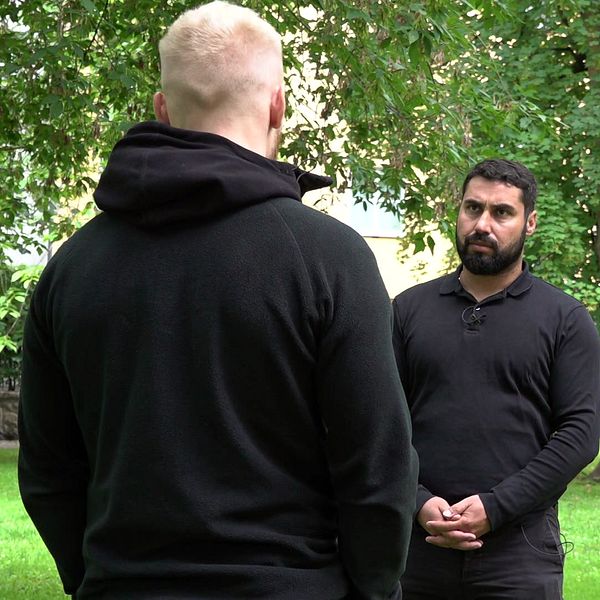 Anonym nlond man med svart hoodie står med ryggen mot kameran