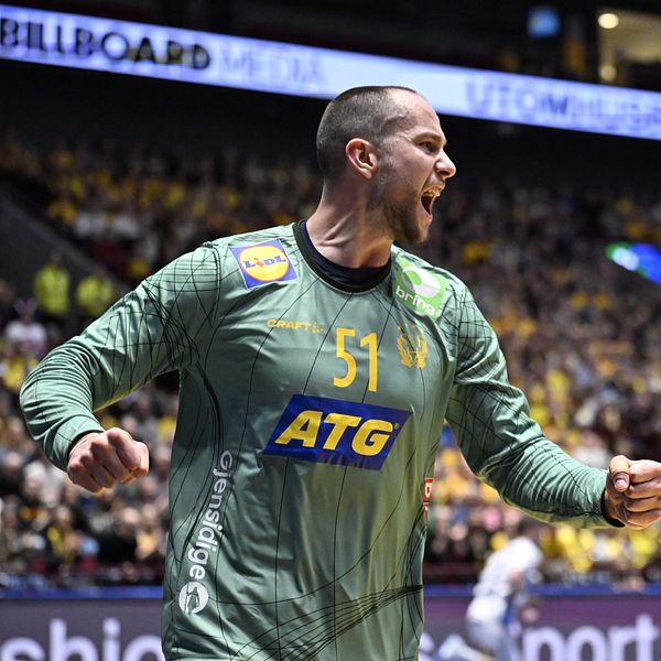 En handbollsmålvakt i grön tröja firar ett mål eller en räddning under en match, med en stor publik i bakgrunden.