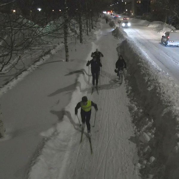 Skidåkare på gatorna i Umeå i mörker.