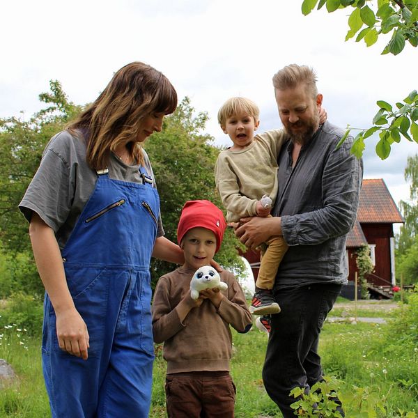 Två föräldrar och två barn i en trädgård.