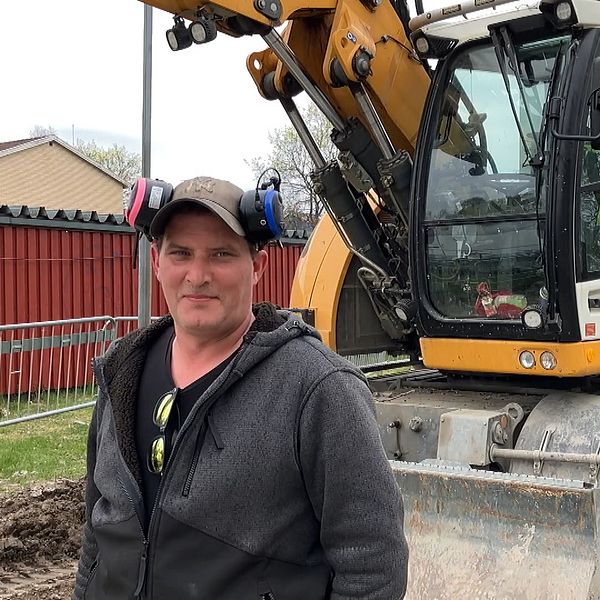 Jonny Emtin kommunstyrelsens vice ordförande i Skinskatteberg framför en grävmaskin.