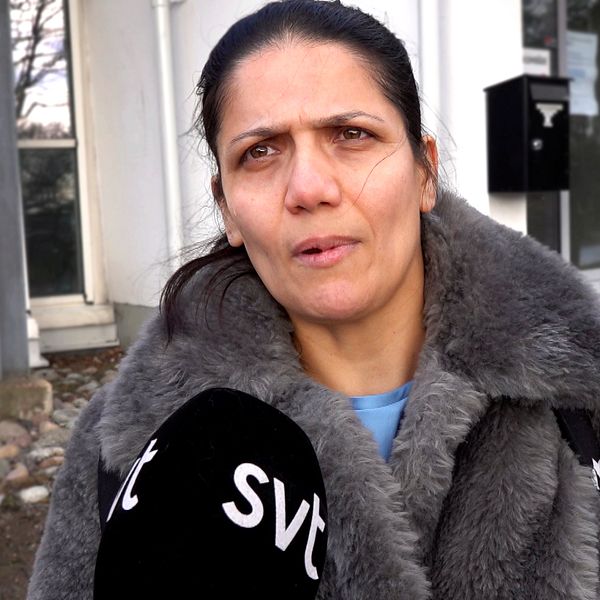 Soraya. klädd i en grå pälsjacka står framför komvux södertälje och pratar in i en mikrofon med SVT-logotyp.