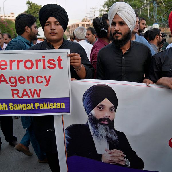 Män med turban håller upp en banderoll med ett porträtt av den mördade sikhledaren Hardeep Singh Nijjar.