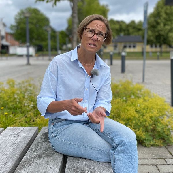 En kvinna sitter på en bänk och berättar.