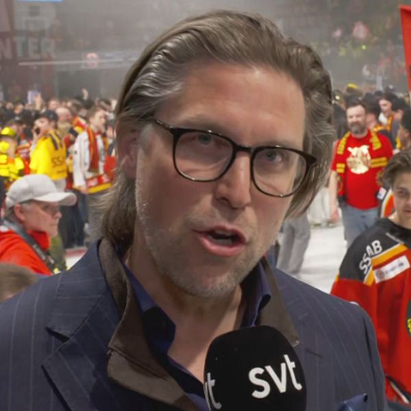 Hockeyfirande på isen, SVT-mikrofon i förgrunden, rödklädda fans och spelare i bakgrunden.