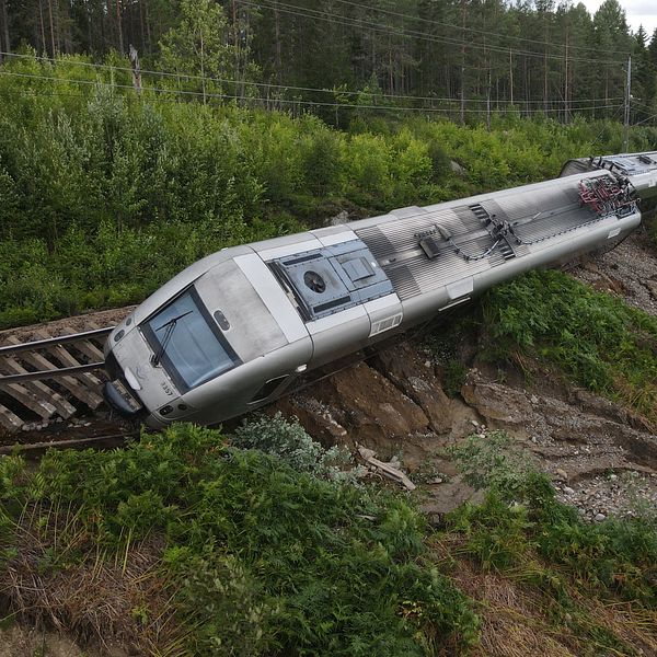 Ett tåg har spårat ur och lutar ner mot en slänt.