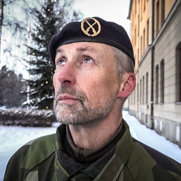 En manlig militär med basker blickar ut över horisonten.