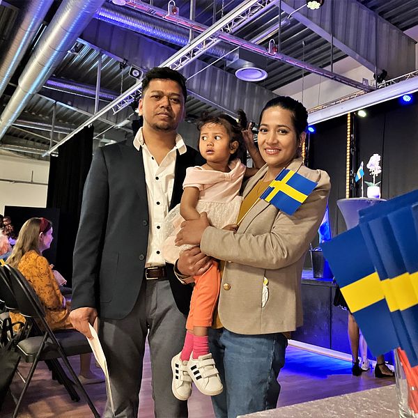 Familjen Barua står framför en scen i Tierp med svenska flaggor bredvid sig