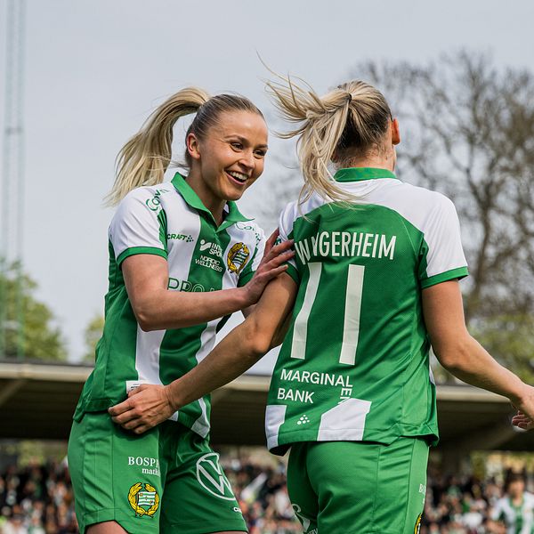 Fotbollsspelare i gröna och vita tröjor firar mål på en utomhusarena med publik.