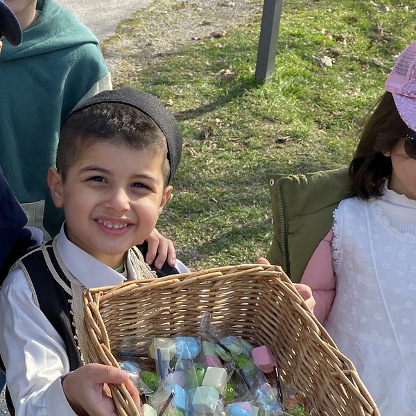 En ung kille står med en korg fylld med godis