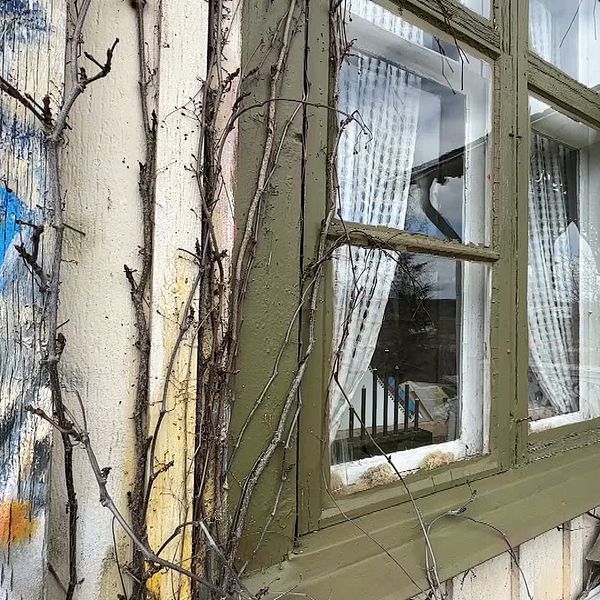 Ett fönster på Marja Myroms hus där en del av hennes konst kan skymtas på fasaden