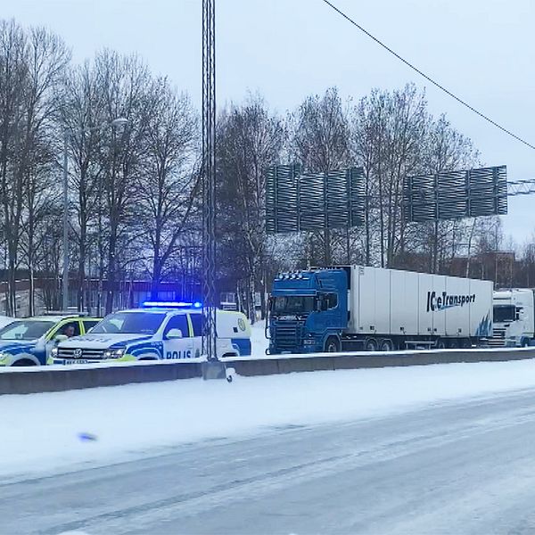 Köer av lastbilar. Längst fram i kön står två polisbilar.