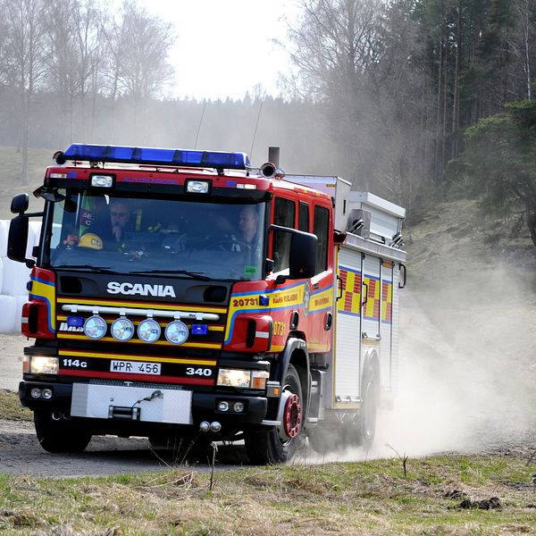 Brandbil på en åker och rök från en mindre gräsbrand.