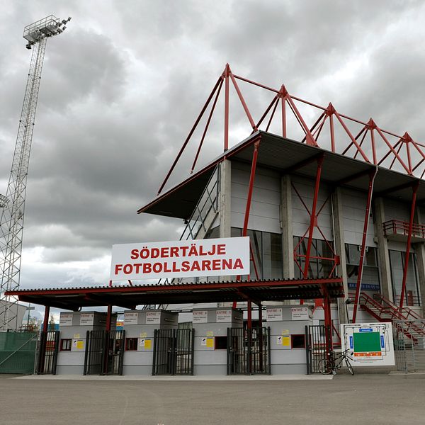 Södertälje fotbollsarena under molnig himmel, entré och läktare syns tydligt.