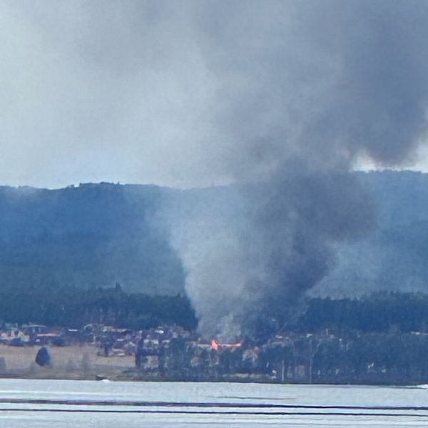 Stort rökmoln från en brand på andra sidan av en sjö