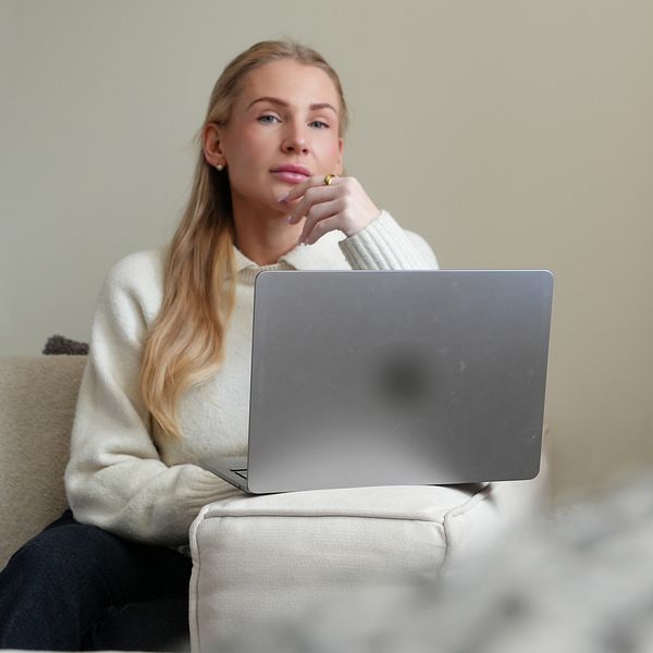 Sofie Gullström sitter i soffa och använder en laptop.