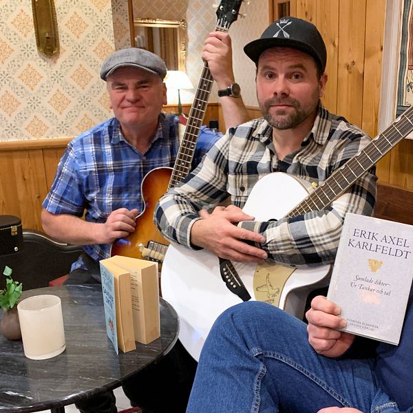 Tre av medlemmarna i Larz Kristerz sitter i en soffa. Två av dem håller instrument i händerna, den tredke en bok av Erik Axel Karlfeldt.