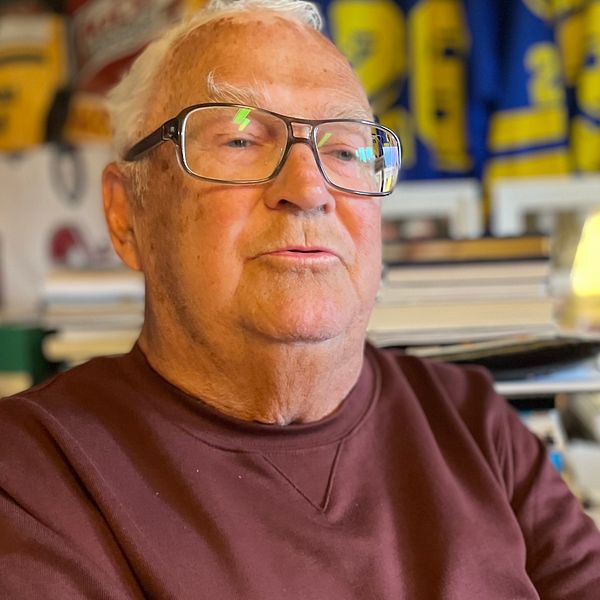 Hasse Andersson på sitt kontor omgiven av sina hockeytröjor.