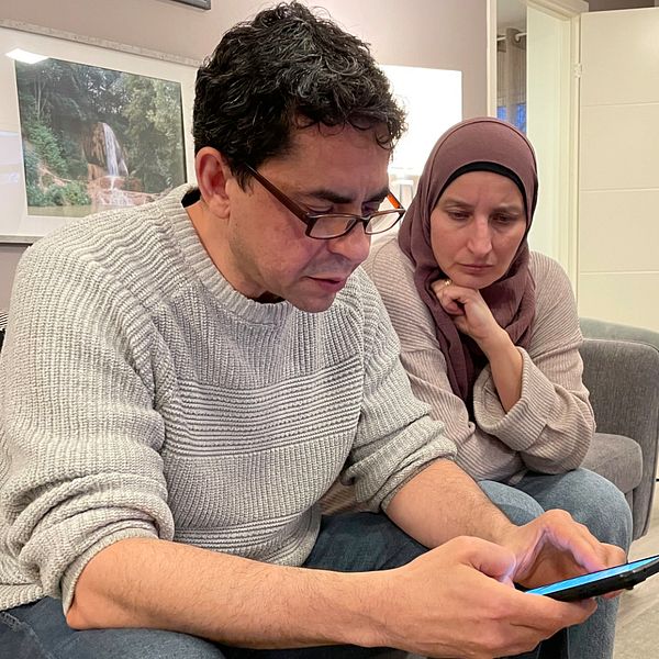 Walid Hams från Strövelstorp sitter i sitt hem med en telefon i handen. Bredvid honom sitter hans fru.