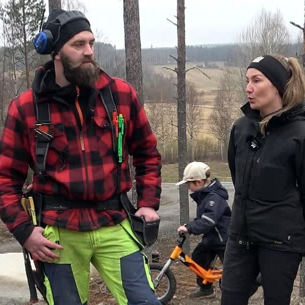 Fyra personer utomhus i skog, ett barn håller docka, ett annat barn sitter på cykel.