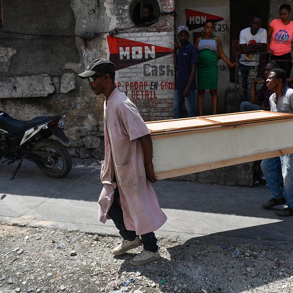 Två personer bär en kista i Port au Prince i Haiti.