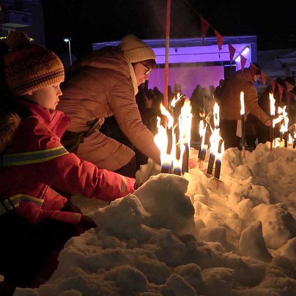 Manifestation för mördade Tintin i Luleå, människor som lämnar ifrån sig sina facklor i snön.