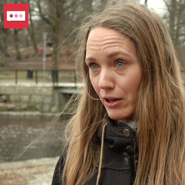 Person med långt, blont hår står vid en kanal med en bro i bakgrunden. Storstadsmiljö.