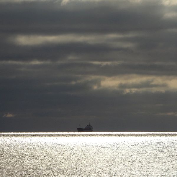 Fartyg vid havshorisonten mot en molnig himmel.