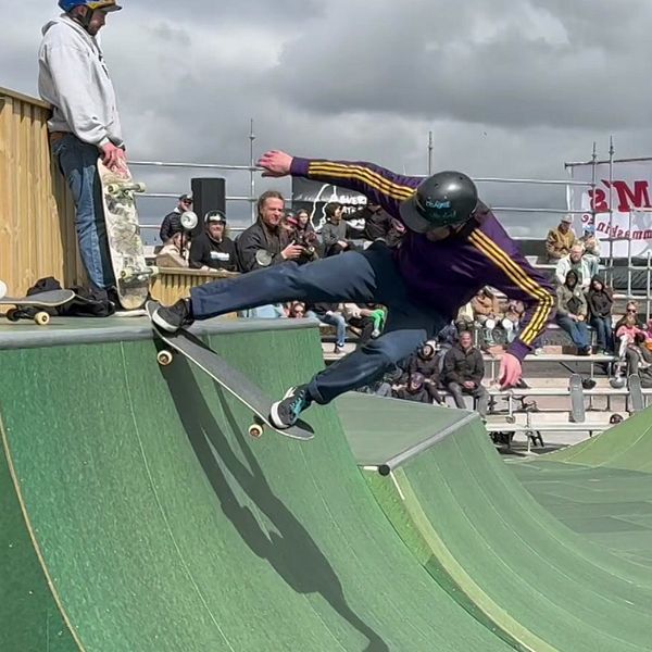 Skateboardåkare gör trick i en ramp inför publiktävling utomhus.