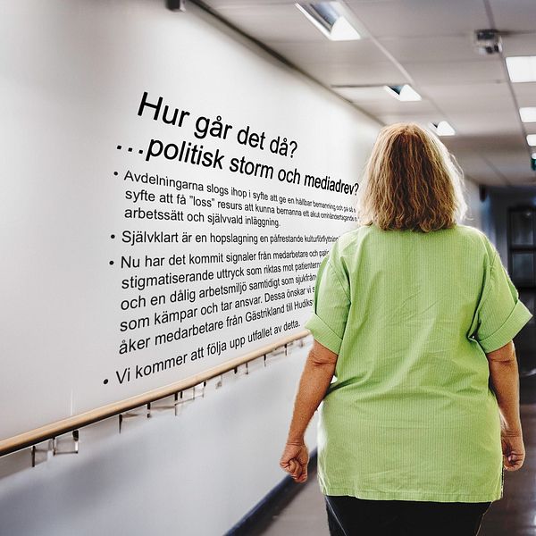 En kvinnlig sjukvårdare med limegrön tröja går i en korridor med text på väggen.