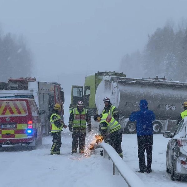 Räddningstjänst sågar mitträcke framför en krashad lastbil