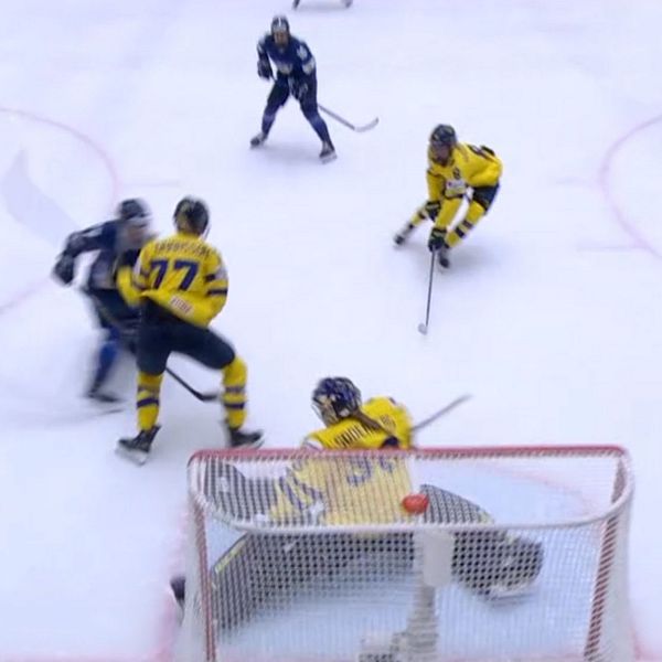 Ishockeyspelare i gula tröjor försvarar mål mot anfallande spelare i mörka tröjor.