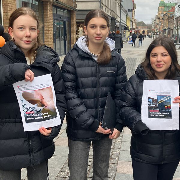 Fyra personer visar fejkade sociala medier inlägg på en gågata.