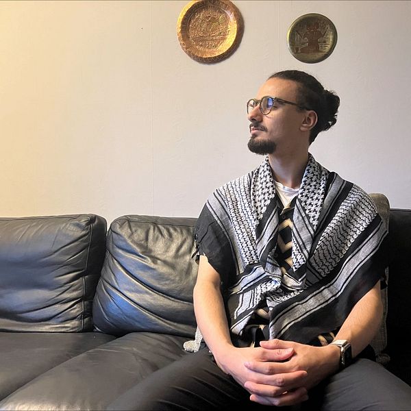 Yazan Abushammalas sitter i en svart soffa.