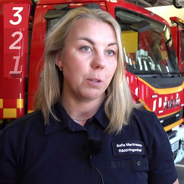 Brandfordon i en brandstation med en person i branduniform framför.