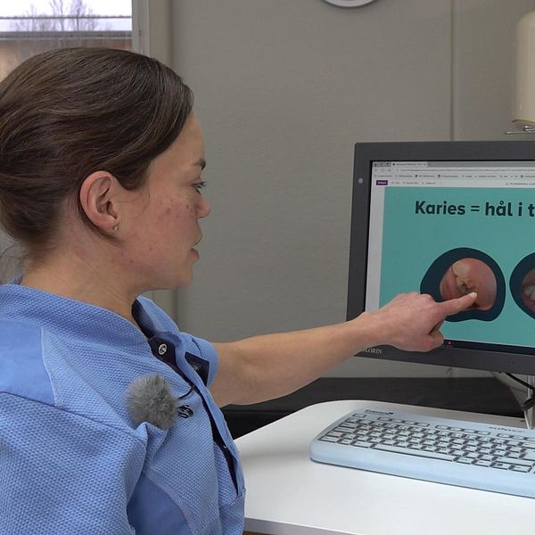 Tandläkaren Maria Wattsgård pekar på en skärm där en bild på en tand med karies syns.