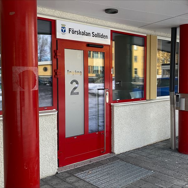 Entrén till Förskolan Solliden i Östersund. Dörren är röd och det är röda pelare. Det är lite snö på marken.