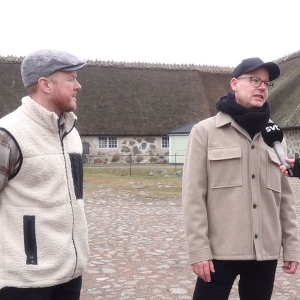 Reporter intervjuar två personer utomhus på en gårdsplan till Slottslängorna i Sölvesborg. De står på kullersten.