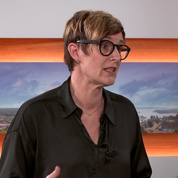 Person i en TV-studio med färgglad bakgrund.