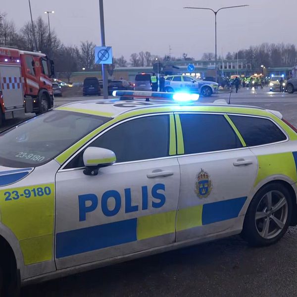 Polisbil vid olycksplats med räddningsfordon och blåljus