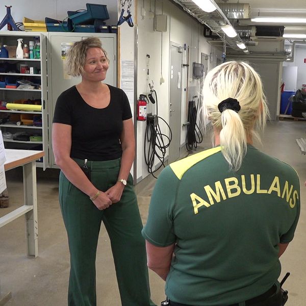 Tre kvinnor som pratar med varandra i ett ambulansgarage